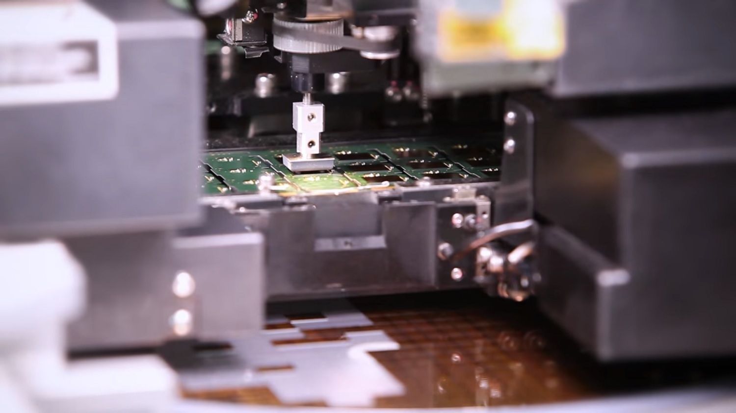 Una macchina prende un chip dall’alimentatore e lo posiziona sulla PCB